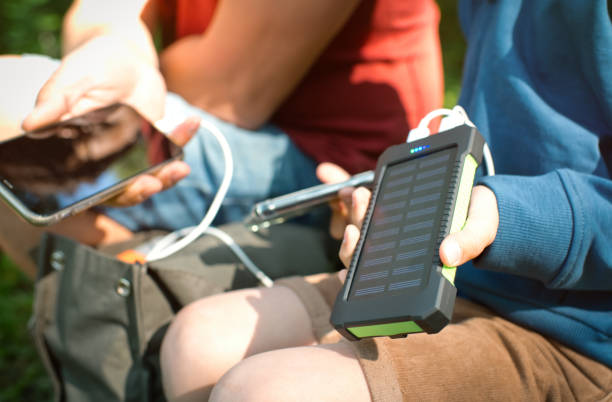 der kleine junge und sein vater verwenden tragbare solarbatterien, um smartphones in der natur aufzuladen. nachhaltiger lebensstil, ökologische alternative energien und ökologische konzepte. - energy fuel and power generation futuristic solar energy stock-fotos und bilder