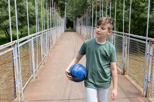 A boy crosses the bridge after football training.