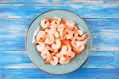 Fresh prawns. Raw shrimps, prawns in a plate on a blue background. Seafood.