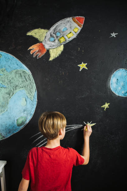 istock Boy drawing rocket and stars next to a planet earth chalk drawing 1500361845