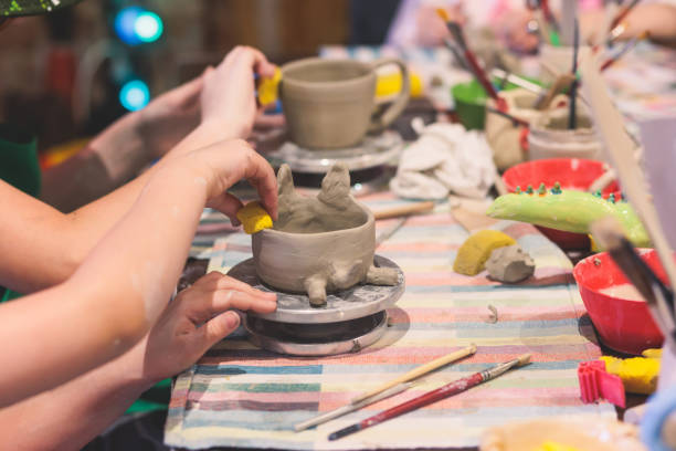 istock Pottery lesson master class for kids children, process of making clay pot on pottery wheel, potter wet hands creating ceramic crockery handcrafts, ceramist molding jar or vase 1500363802