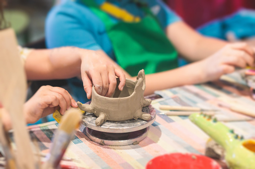 Pottery lesson master class for kids children, process of making clay pot on pottery wheel, potter wet hands creating ceramic crockery handcrafts, ceramist molding jar vase