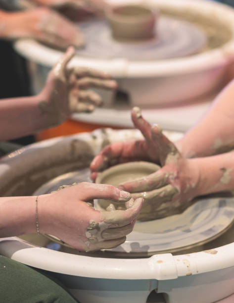 Pottery lesson master class for kids children, process of making clay pot on pottery wheel, potter wet hands creating ceramic crockery handcrafts, ceramist molding jar or vase Pottery lesson master class for kids children, process of making clay pot on pottery wheel, potter wet hands creating ceramic crockery handcrafts, ceramist molding jar vase homemade pottery wheel stock pictures, royalty-free photos & images