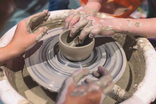 istock Pottery lesson master class for kids children, process of making clay pot on pottery wheel, potter wet hands creating ceramic crockery handcrafts, ceramist molding jar or vase 1500363892