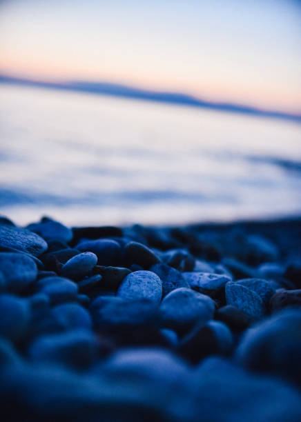 Relaxing beach with Pebble stones and small waves at sunset