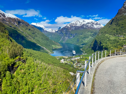 Geirangerfjord, Iceland-May 30, 2023-A luxury cruise ship is docked far below at the end of Geiranger Fjord for a brief visit to allow its passengers to enjoy this magnificent scenery for a few hours.