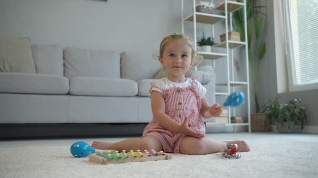Child plays with wooden xylophone and maracas.