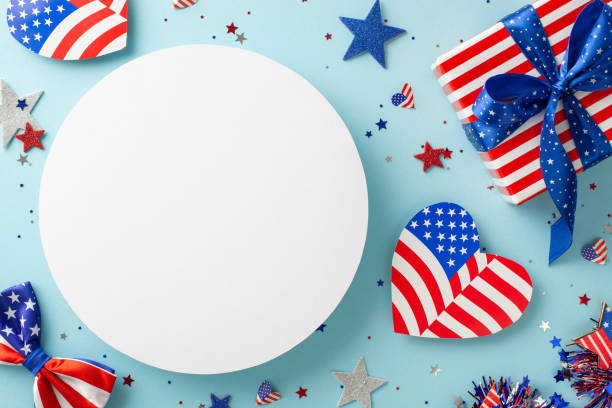 istock American Independence congratulatory scene. Top view of representative items: hearts patterned with flag design, glistening stars, giftbox, bow-tie on pastel blue surface with circle for greeting 1500376996