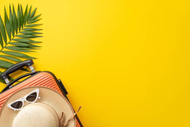 istock Summer retreat inspiration. Top view composition featuring a suitcase, beach gear, sunglasses, sunhat, and green palm leaf against a striking yellow backdrop. Perfect for text or promotional content 1500378246