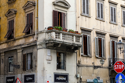 Florence, Italy - April 13, 2023: Balcony almost at the corner of the facade of a townhouse in the old town. The windows in this building are equipped with shutters.