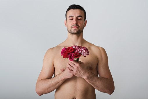 front view portrait of a shirtless carefree man enjoying a poetic moment with closed eyes on a white background