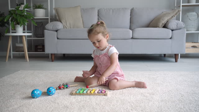 Child plays with wooden xylophone and maracas.