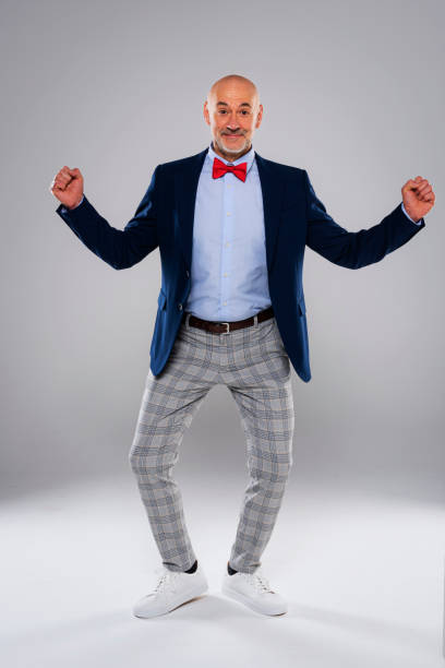 istock Man wearing bow tie and checked pants while standing at isolated grey background 1500388732