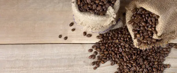 Fresh coffee beans. Coffee beans in bags on a wooden background. View from above. Copy space. Banner