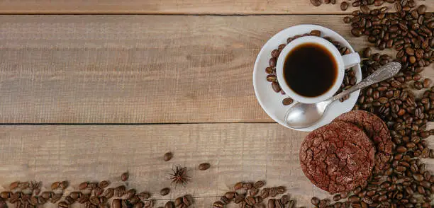 Fresh coffee. A cup of fresh aromatic coffee. Coffee cookies. Grains on a wooden background. View from above. Copy space. Banner