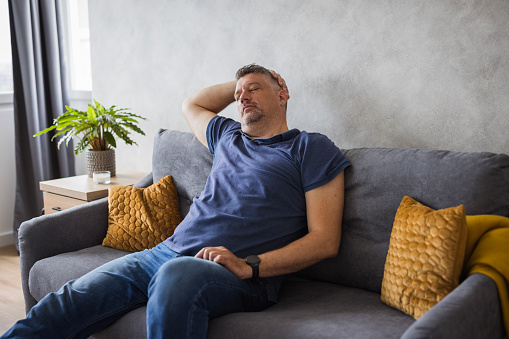 Close up relaxed man with hands behind head resting in cozy armchair at home, enjoying lazy weekend, mindful peaceful young male with closed eyes leaning back, taking nap, sleeping or daydreaming