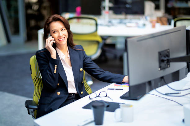 istock Confidient professional woman sitting at desk and surrounded by computers while working at the office 1500404128