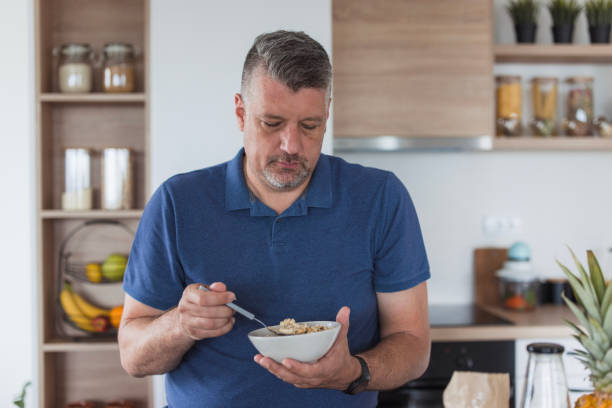 istock Man standing in a kitchen and eating cereal breakfast 1500404820