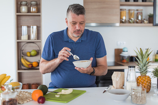 Man eating healthy, having cereals and fruit for breakfast