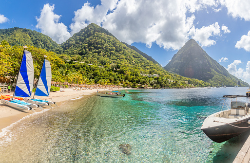 Caribbean beach with palms, turquoise water and boats on the shore with Gros Piton mountain in the background, Sugar beach, Saint  Lucia