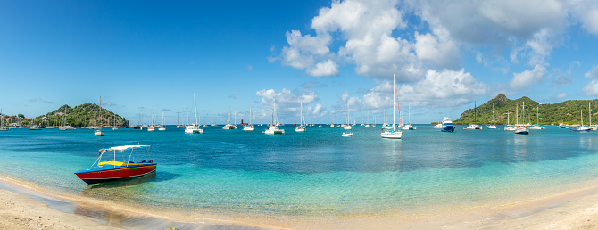 Turquoise colored sea with ancored yachts and boats in the lagoon with sandy beach at Carriacou island, Grenada, Caribbean sea