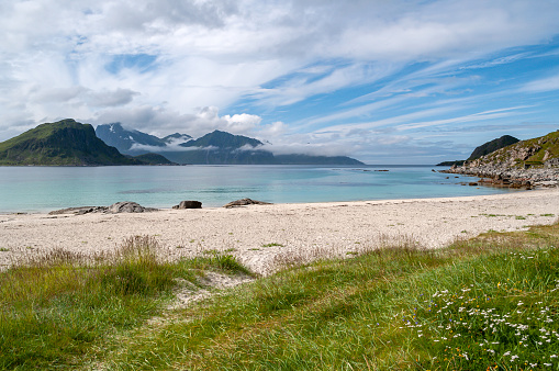 Sandy beach with sea and mountains in the clouds - Haukland beach, Lofoten, Norway