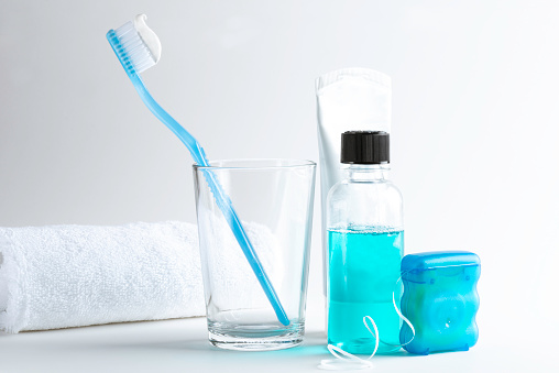 Dental equipment like tooth paste, tooth brush, blue mouth wash and dental floss on white background.