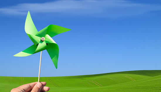 Green clean energy concept. ESG and Green Power. Hand holding a green paper pinwheel.