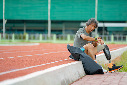 Asian old man with disabilities sitting and resting before running race