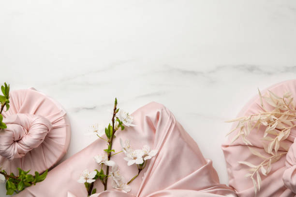 istock Furoshiki technique. Gifts packed in pink fabric on white marble table, flat lay. Space for text 1500413833
