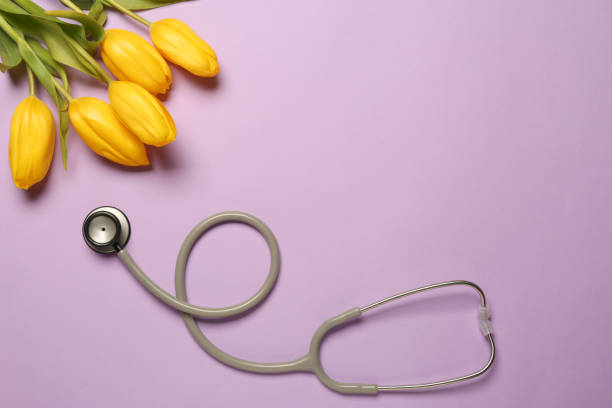 istock Stethoscope and yellow tulips on violet background, flat lay with space for text. Happy Doctor's Day 1500413865