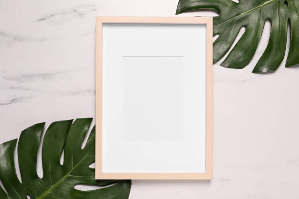 istock Empty photo frame and green leaves on white marble background, flat lay. Space for design 1500413927
