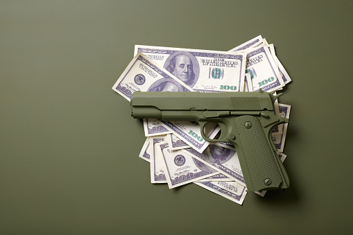 green gun with money on a green background