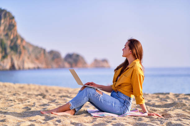 istock Young millennial freelancer girl using laptop on the beach by sea. Dream office work concept 1500415621