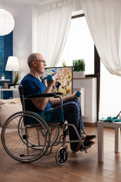 istock Invalid senior man in wheelchair holding workout dumbbells practicing arms exercise 1500415782
