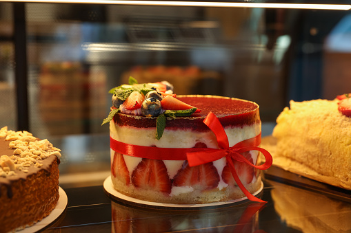 Delicious cake with strawberries on counter in bakery shop, closeup