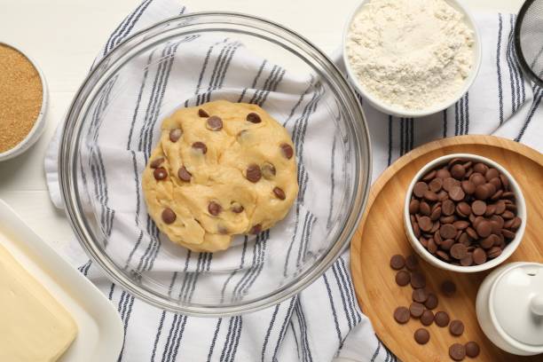 istock Fresh dough and different ingredients for cooking chocolate chip cookies on white table, flat lay 1500420647