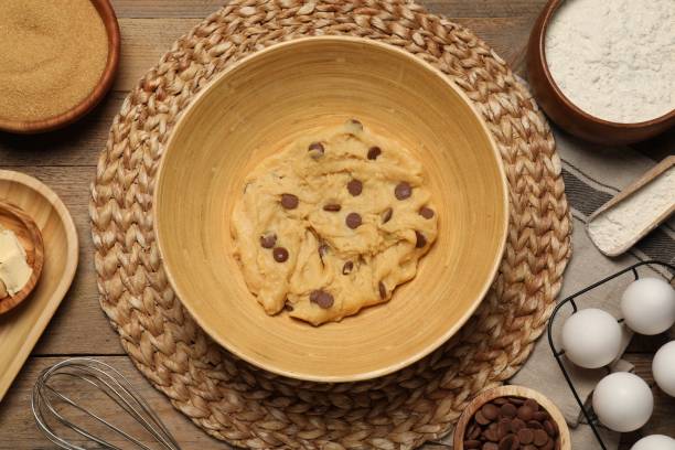 istock Fresh dough and different ingredients for cooking chocolate chip cookies on wooden table, flat lay 1500420670