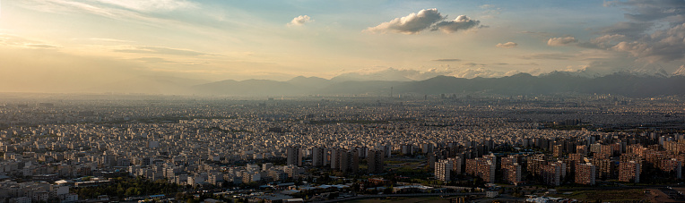 The cityscape of Tehran during the sunset with the view of the Milad tower and the Mountains