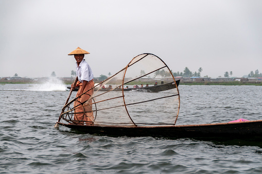 Nyaung  Shwe, Inle Lake, Myanmar - nov 10,2012 : Lake fishermen prepare their characteristic fishing nets early in the morning on the calm waters of Inle Lake