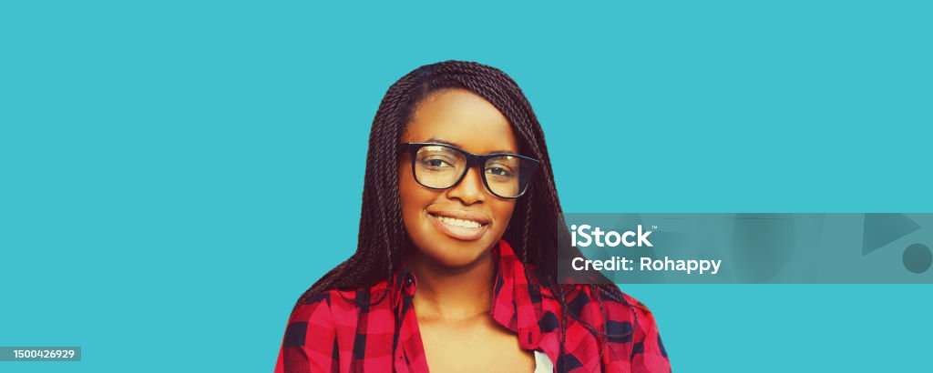 Portrait of young smiling african woman wearing eyeglasses isolated on blue background 20-24 Years Stock Photo