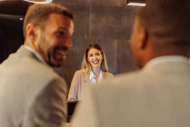 istock Hotel receptionist talking and laughing with two men booking hotel room 1500427376