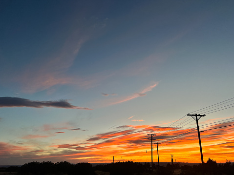phone lines that bind us as humans intersect with the grandeur of a beautiful sunset.
