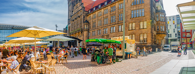 Chemnitz, Saxony, Germany, June 21, 2022: Panorama. Outdoor street cafÃ© and restaurants with umbrellas in the historic downtown of Chemnitz, at blue sky and sunny summer day
