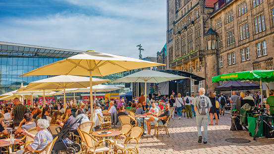 Chemnitz, Saxony, Germany, June 21, 2022: Outdoor street cafÃ© and restaurants with umbrellas in the historic downtown of Chemnitz, at blue sky and sunny summer day