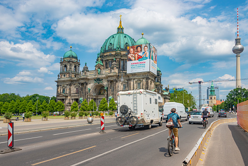 Famous central Unter den Linden street, Berlin Cathedral (Berliner Dom) in historical and business downtown of Berlin, with a camper and cyclist on road, Germany, at summer sunny day and blue sky