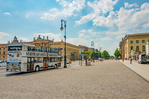 Famous central Unter den Linden street in historical and business downtown of Berlin, with a touristic sightseeing bus, Germany, at summer sunny day and blue sky