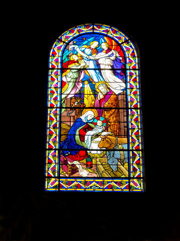 Vertical photo of the beautiful colourful stained glass window depicting Saint John the Evangelist, holding a golden goblet containing a purple dragon, with the Heraldic Eagle of St John at his feet, as seen from inside the heritage listed Saints Mary and Joseph Catholic Cathedral, Armidale, New England high country, northern NSW.