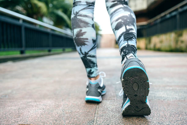 Woman legs ready to run wearing sneakers and tropical leggings stock photo