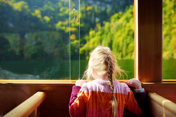 Little girl enjoying a view of deep green waters of Konigssee while traveling by electric boat stock photo